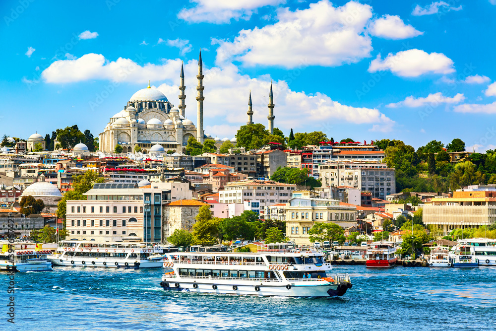 Obraz premium Touristic sightseeing ships in Golden Horn bay of Istanbul and view on Suleymaniye mosque with Sultanahmet district against blue sky and clouds. Istanbul, Turkey during sunny summer day.