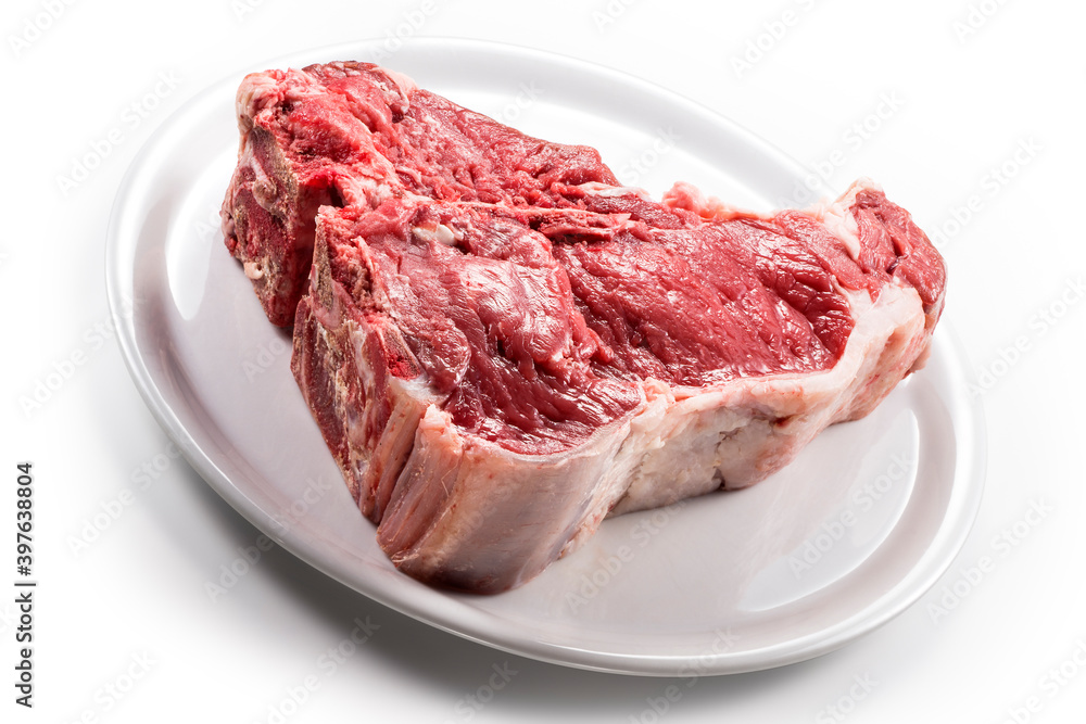 Raw T-bone steak on white round plate Raw T-bone steak on white round plate