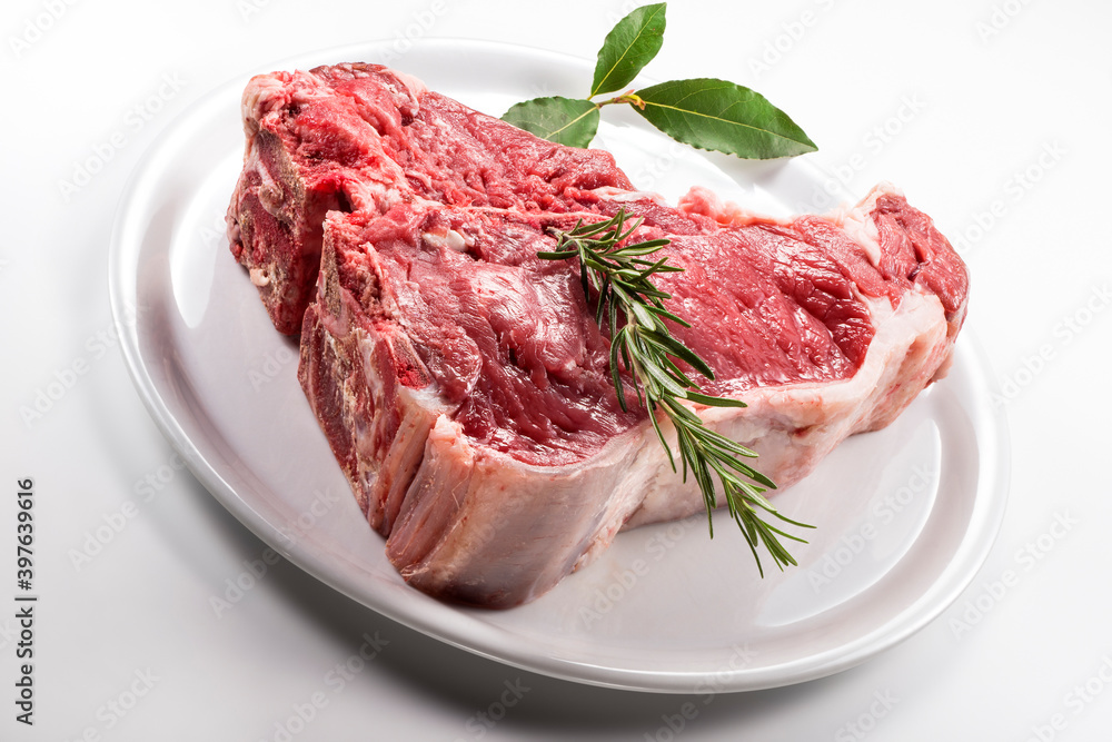 Raw T-bone steak with bay leaf and rosemary