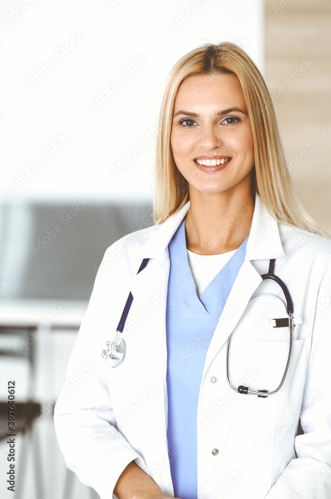 Woman-doctor at work in clinic excited and happy of her profession. Blond female physician is smiling while using tablet computer. Medicine concept Woman-doctor at work in clinic excited and happy of her profession. Blond female physician is smiling while using tablet computer. Medicine concept