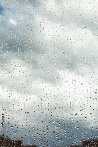 Close up of a window with rain drops falling down. Focus on rain drops. Rain drops on rainy day on outside window glass with blurred edges. Rain outside window pane in spring day. © Мария Чичина