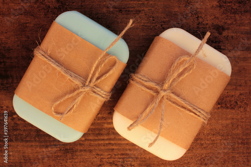 Handmade soap bars in craft wrapping paper on wooden table. 