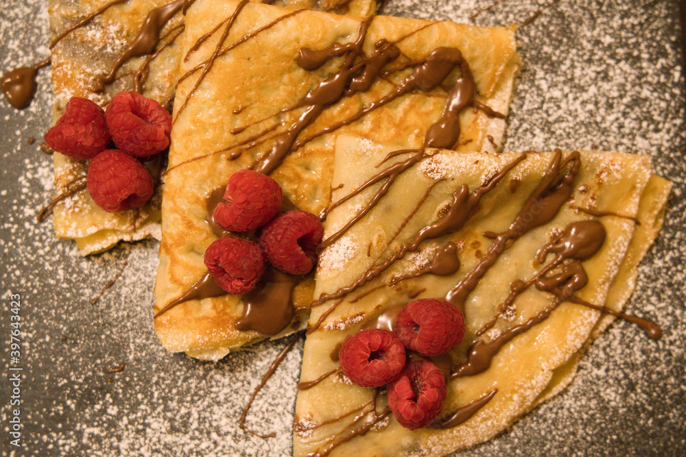 Crepes filled with chocolate with raspberries and glazed sugar Crepes filled with chocolate with raspberries and glazed sugar