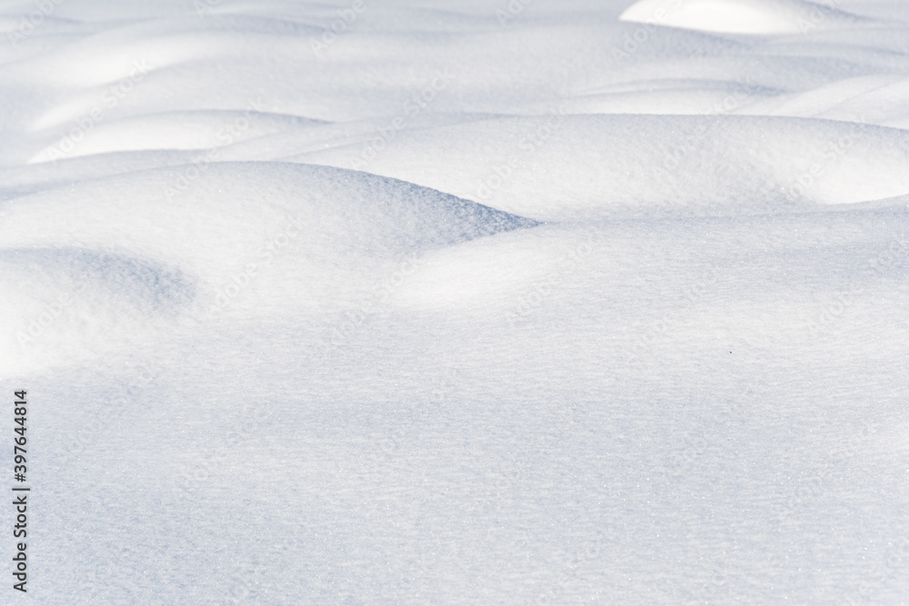 Smooth snow drifts on sunny winter day. Deep and high snow drifts illuminated by sunlight and being in shadow Smooth snow drifts on sunny winter day. Deep and high snow drifts illuminated by sunlight and being in shadow