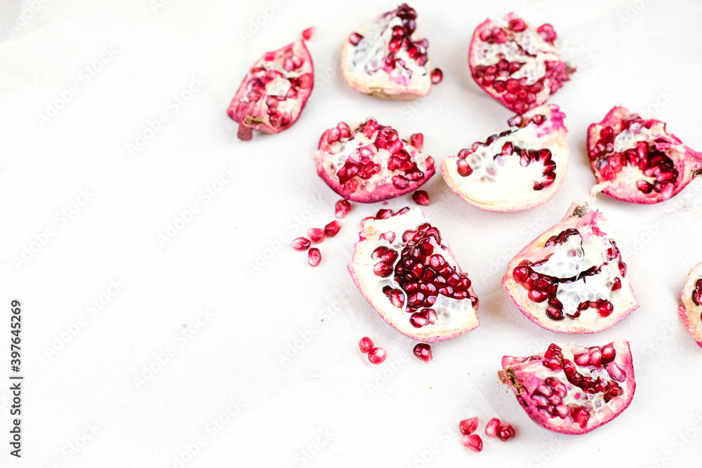 several open red pomegranate fruits with grains on a white cloth. several open red pomegranate fruits with grains on a white cloth.
