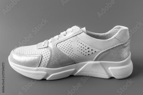 One white women's leather sneaker on a gray background