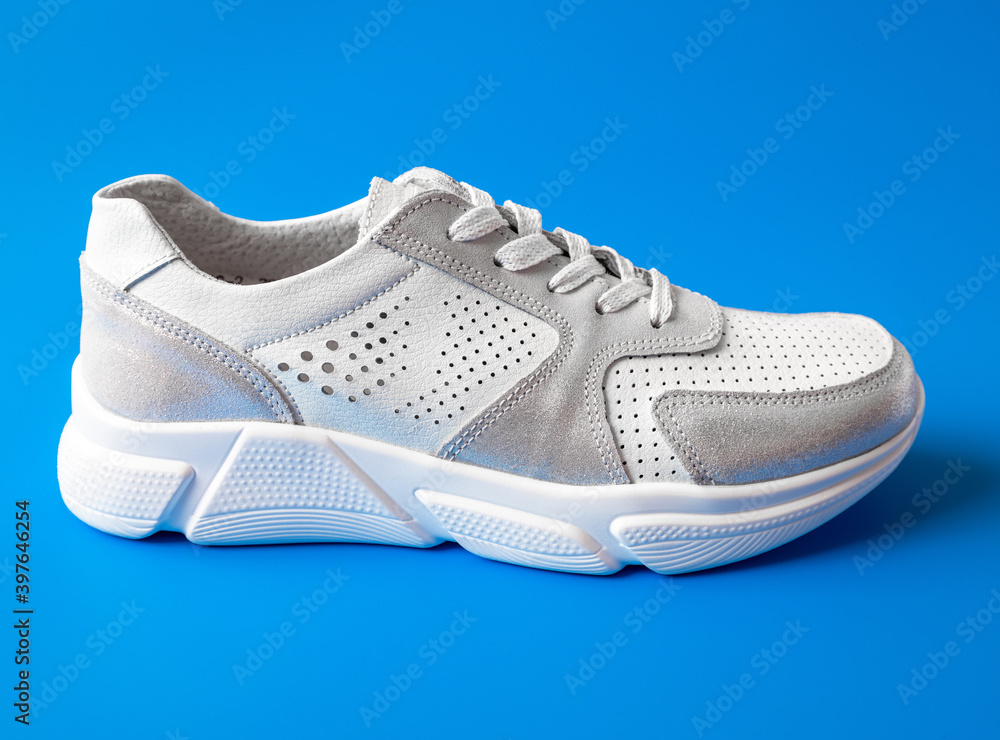 One white women's leather sneaker on a blue background One white women's leather sneaker on a blue background
