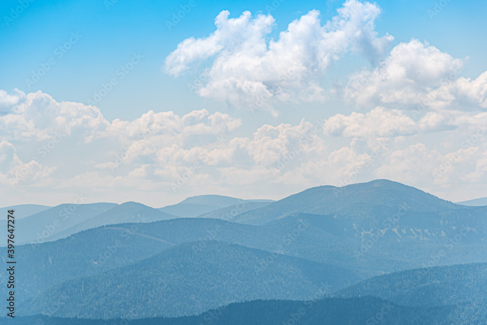 Thick clouds over mountain range, hills in blue haze