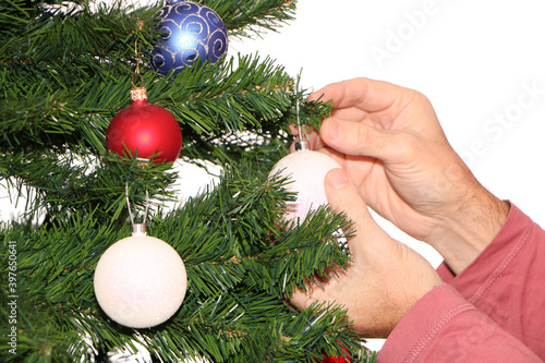 A man decorates a Christmas and New Year tree with festive balls.