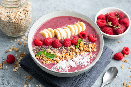 Pink raspberry smoothie bowl with superfood toppings. Healthy vegan smoothie bowl
