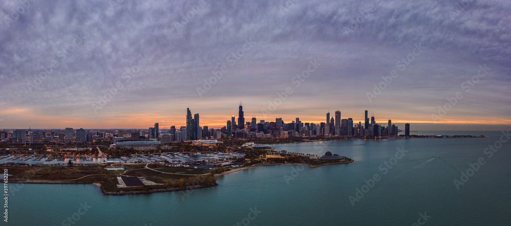 Wide angle Chicago city skyline aerial panorama with Northerly Island and Lake Michigan in foreground and highrise skyscraper buildings along the horizon with a beautiful orange and blue sunset sky. Wide angle Chicago city skyline aerial panorama with Northerly Island and Lake Michigan in foreground and highrise skyscraper buildings along the horizon with a beautiful orange and blue sunset sky.