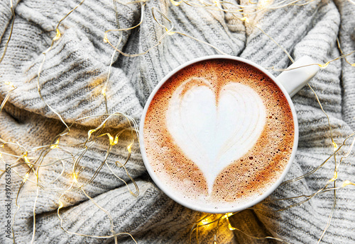 Сoffee with a heart pattern on a warm knitted sweater