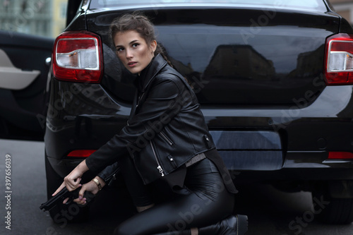 A girl with a gun in her hands on the background of a car