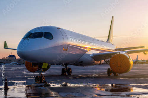 Modern passenger airplane on the airport apron against the backdrop of a scenic sunset