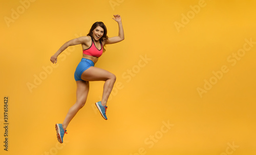 Fototapeta Naklejka Na Ścianę i Meble -  Sport woman runs on yellow background. Happy and joyful expression.