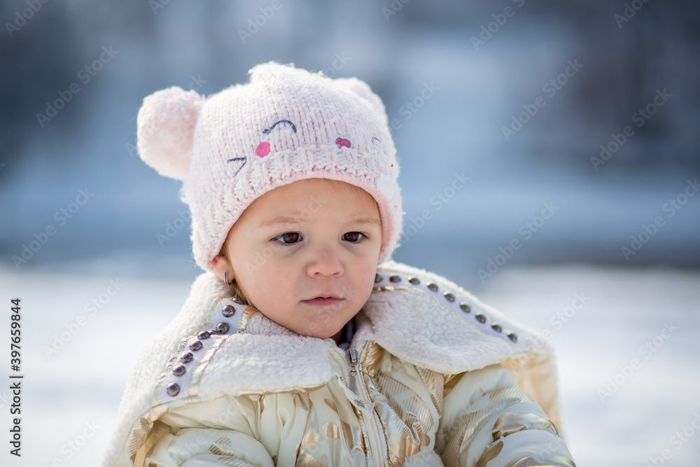 Little girl in white jacket having fun, playing outside, surrounded with snow. Little girl in white jacket having fun, playing outside, surrounded with snow.
