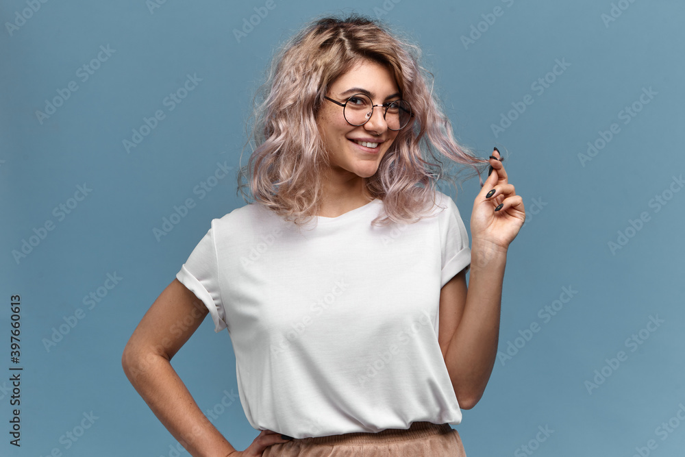 Youth, beauty, style and fashion concept. Portrait of cute playful young woman with pinkish hair and nose ring posing isolated in round glasses, looking at camera with charming flirty smile - obrazy, fototapety, plakaty 