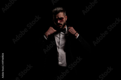 attractive elegant man with sunglasses adjusting tuxedo