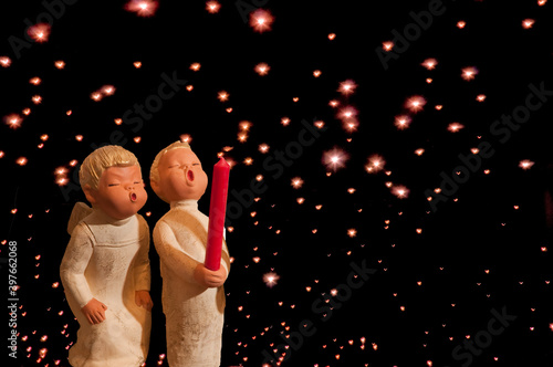 Weihnachten Engel pusten zu einer roten Kerze