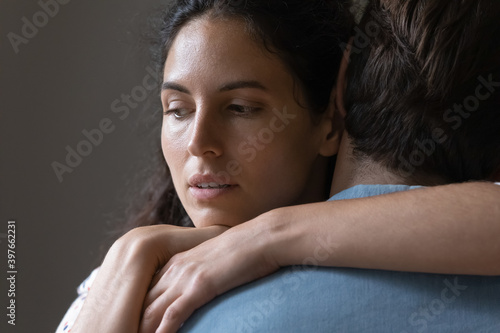 Close up thoughtful young woman hugging man, looking in distance, thinking about marriage problems, suspicious doubting wife embracing husband, pondering cheating in relationship, break up photo