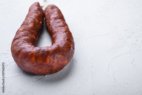 Dry cured chorizo sausage on white textured background with copy space