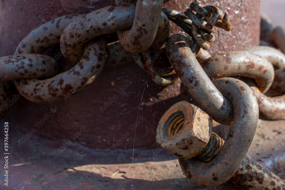 Fastening the chain with a large bolt. At the end of the chain is an old rusty bolt. Securing the ship with a large chain. Old rusty vintage mooring bollard for boats, ships and yachts. Fastening the chain with a large bolt. At the end of the chain is an old rusty bolt. Securing the ship with a large chain. Old rusty vintage mooring bollard for boats, ships and yachts.