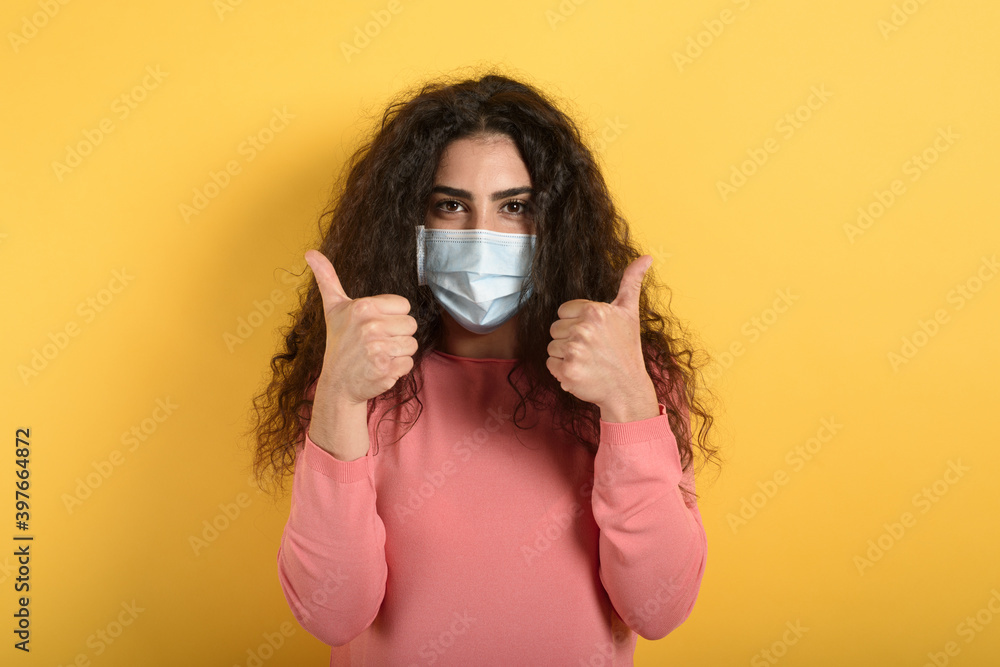 Obraz premium Girl is optimistic about the defeat of covid 19 coronavirus. yellow background.