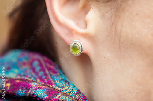 Female ear wearing elegant silver olivine gemstone earring