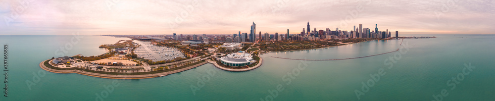 Fototapeta premium Incredible wide angle Chicago city skyline aerial panorama over Lake Michigan with highrise skyscraper buildings and boat harbors along the horizon with a beautiful orange and blue sunset sky above.