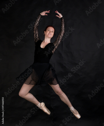 Beautiful dancer studio portrait jumping on black background. © idea_studio