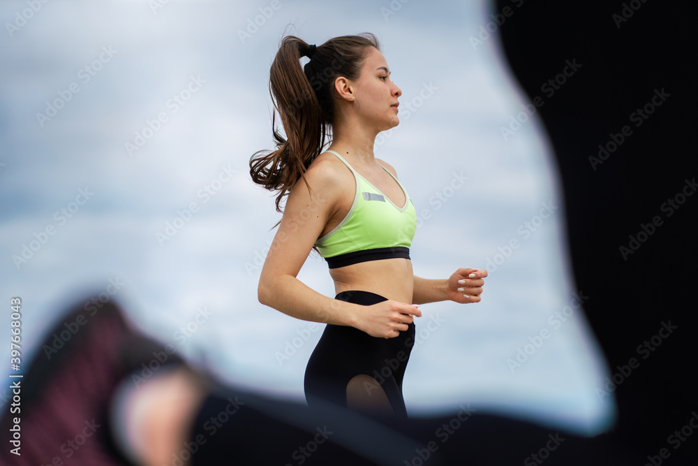 © Georgii - Running marathon athletic girl, female jogging outdoors on group workout, close up photography © Georgii - Running marathon athletic girl, female jogging outdoors on group workout, close up photography