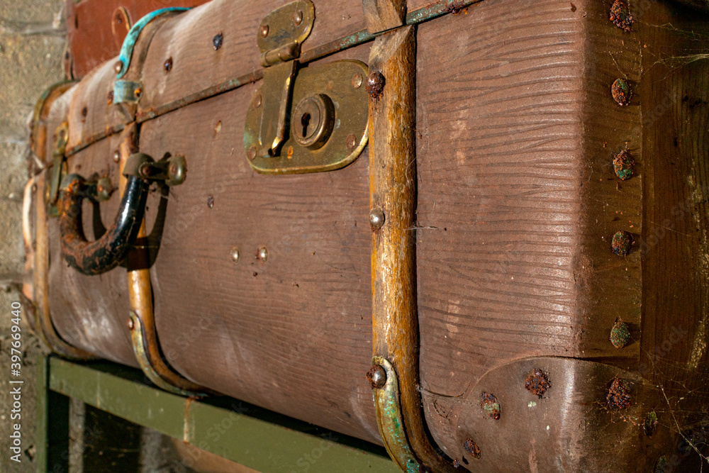 Naklejka premium Old vintage suitcases on a shelf in abandoned garage. Corrosion on locks and handle. Dust and cobwebs on the walls.