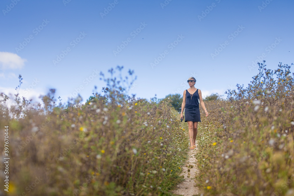woman in field taking pictures, walking and relaxing