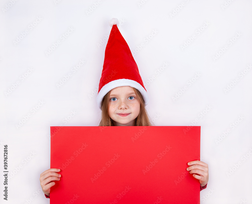 A beautiful girl in a high Christmas cap holds a red paper background in front of her. A beautiful girl in a high Christmas cap holds a red paper background in front of her.