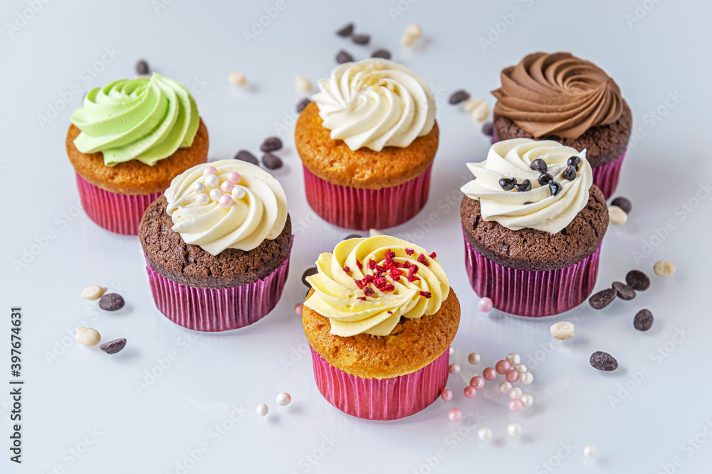 assorted cupcakes and decor for them on a light glass surface close up
