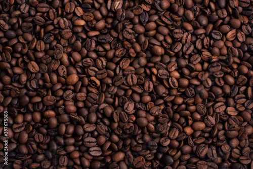 Scattered piles of roasted arabica coffee beans top view in daylight