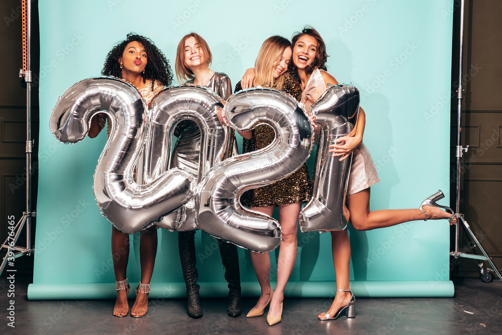 Obraz premium Beautiful Women Celebrating New Year.Happy Gorgeous Female In Stylish Sexy Party Dresses Holding Silver 2021 Balloons, Having Fun At New Year's Eve Party. Holiday Celebration.Charming Models