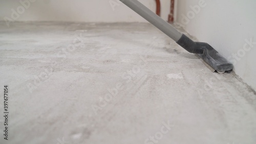 Preparing the concrete floor for priming with a vacuum cleaner. Worker cleaning floor with vacuum cleaner from industrial concrete dust and cement dirt during home renovation work.