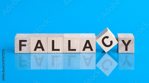 the text FALLACY is written on the cubes in black letters, the cubes are located on a blue glass surface