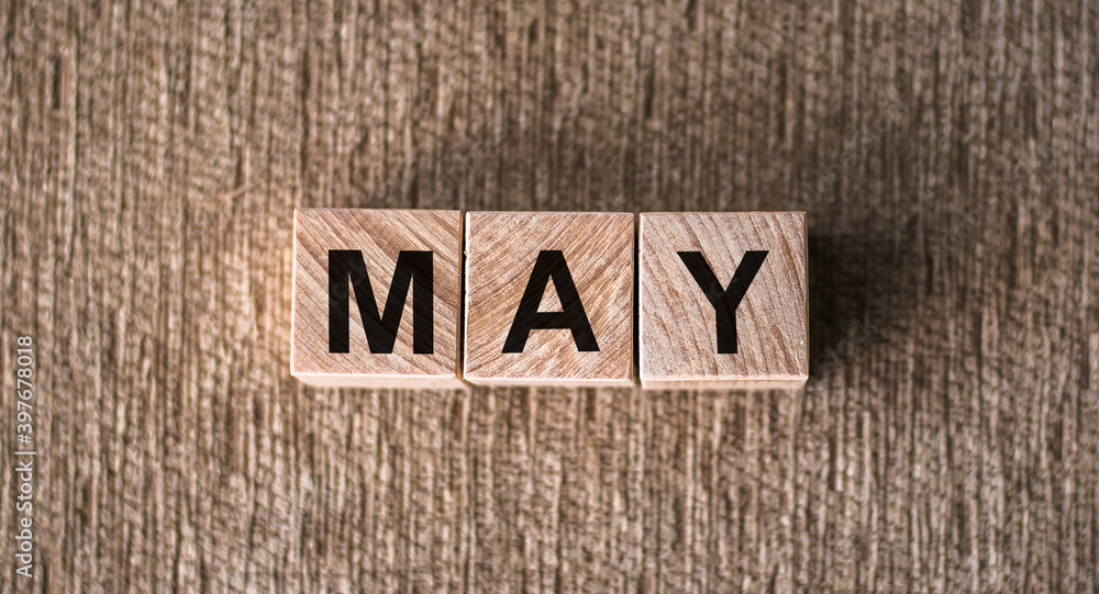 MAY is a word written on wooden cubes. On a brown background for your design, top view. MAY is a word written on wooden cubes. On a brown background for your design, top view.
