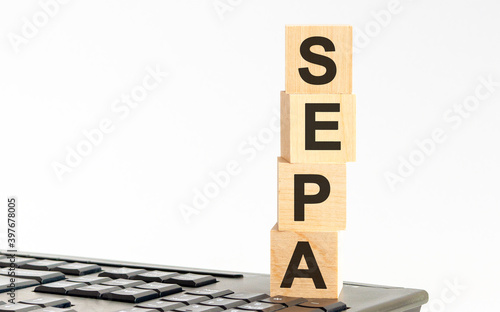 Concept image a wooden block and word - SEPA - on white background. The cubes are located on the keyboard. Selective focus. photo