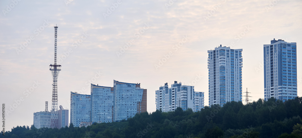 morning cityscape against the sky, multi-storey residential buildings and a TV tower on the top of the hill