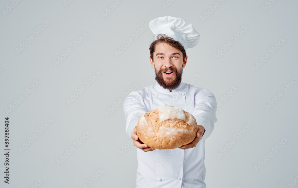 Happy cook in connected clothes holds a loaf of fresh bread in his hand Happy cook in connected clothes holds a loaf of fresh bread in his hand
