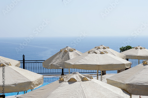 Beach umbrellas near the pool with panoramic views of the Mediterranean Sea. Sea background with space to copy text. The concept of summer holidays. The concept of minimalism.