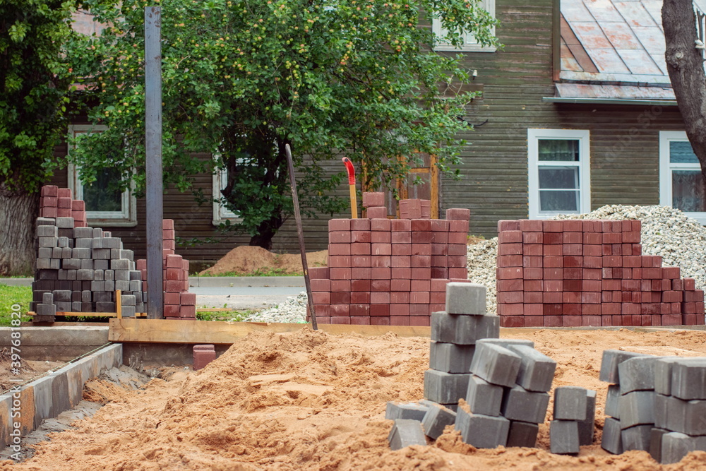 Naklejka premium Street tiles in the form of blocks on the background of a construction site and a fragment of the seetu mansion