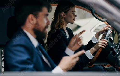 A woman driving a car next to a man colleagues at work trip officials