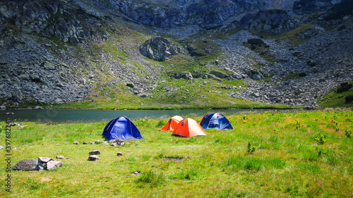 A campsite near a glacial lake at a high altitude in Galcescu Glacier. The steep rocky mountain sides of Lotru Mountains are covered by shady clouds. Carpathian Mountains, Romania