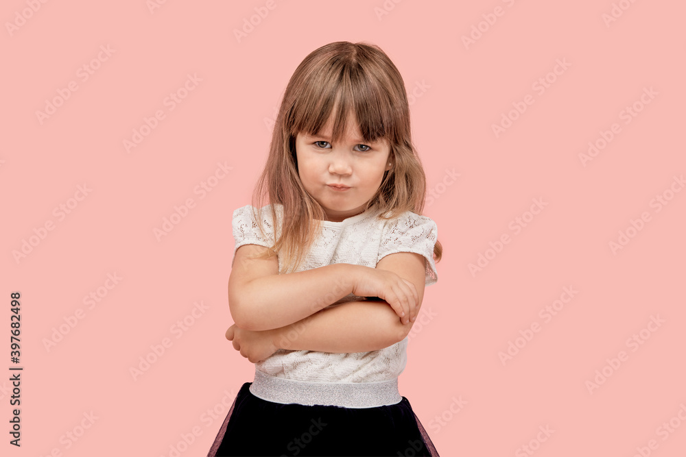 Sad offended beautiful little girl in a white t-shirt looks at the camera. Pink isolated background. Sad offended beautiful little girl in a white t-shirt looks at the camera. Pink isolated background.
