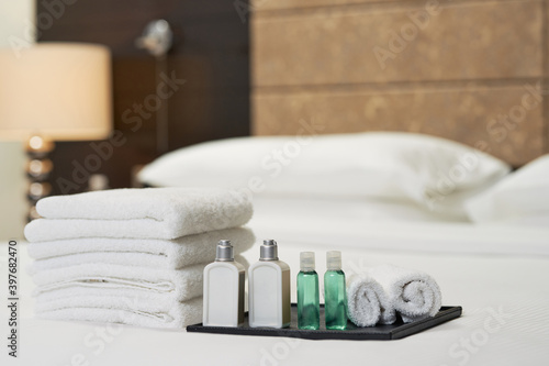 Liquid shampoo and shower gel near towels on bed
