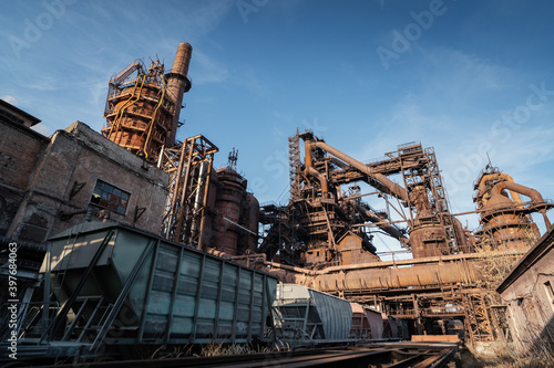 Blast furnace of metallurgical plant or chemical factory with industrial railroad and freight wagons.
